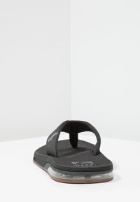 Zwarte flip-flop sandaal met een gevoerde zool, gestructureerd voetbed en dubbele banden met een lichte kromming, ideaal voor casual gebruik.