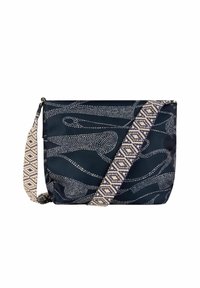 Sac marine avec un motif abstrait de points blancs, doté d'une épaisse bandoulière tissée avec des accents de conception géométrique. Fermeture zippée, texture douce, forme carrée.