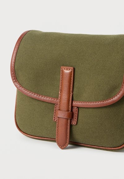 Μικρό υφασμάτινο πουγκί σε ελιά, με καφέ δερμάτινη επένδυση και κεντρικό δερμάτινο λουράκι κλεισίματος σε λευκό φόντο.