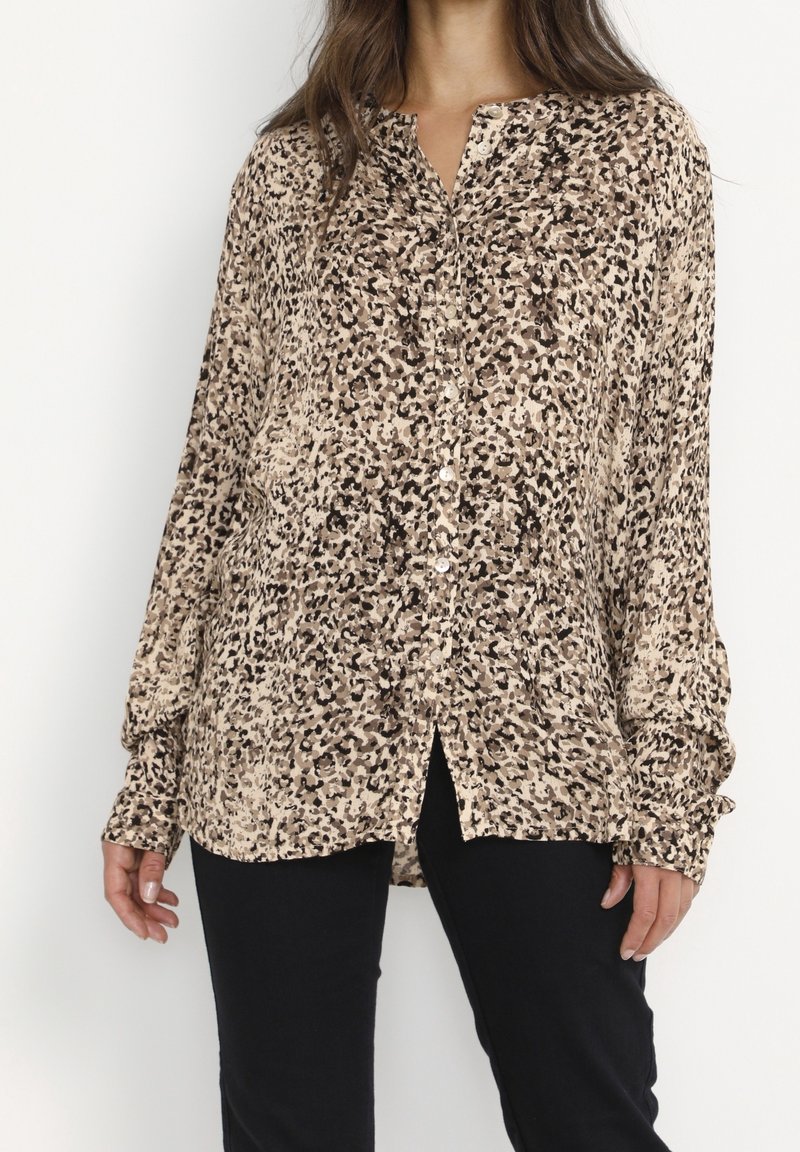 Leopard print button-up shirt in beige and brown tones, featuring a collar, long sleeves, and a relaxed fit with side splits.