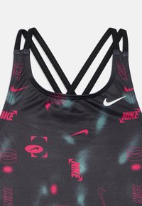 Fekete sportos trikó keresztezett pántokkal. Élénk rózsaszín és cián Nike logók és minták díszítik. Simító, rugalmas anyag.