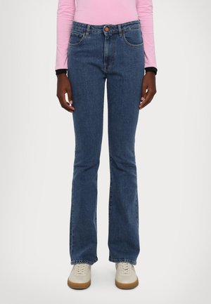 Blue denim flared jeans with a high waist, two front pockets, and a central button. Paired with light-colored sneakers.