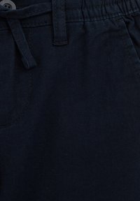 Mörk marinblå tyg med en mjuk textur. Elastisk midja med dragsko, knäppning samt sidofickor.