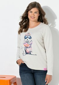 Hellgraues Langarmshirt mit einem bunten Hundemotiv, der eine Schutzbrille und einen Schal trägt. Es hat ein pinkes Etikett auf der unteren linken Seite.