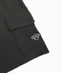 Zwarte cargoshorts met een flapzak, gestructureerde stof, en een ronde patch met een gestileerd aapjes gezicht logo aan de zijkant.