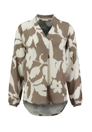Blouse à manches longues avec un motif floral marron et crème, coupe détendue avec un col en V, poignets froncés et un ourlet arrière plus long. Tissu doux et lisse.