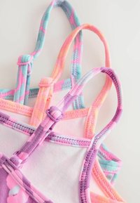 Trois débardeurs ajustables aux couleurs pastel avec des bretelles tie-dye en rose, violet, orange et bleu.