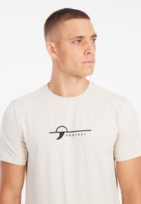 Licht beige kort-lange mouw t-shirt van gestructureerde stof, met een zwart logo-ontwerp dat "PROTEST" op de borst leest.