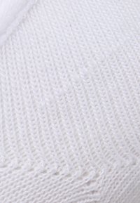 Tissu tricoté blanc avec un motif texturé, présentant un tissage en diagonale et une finition lisse. La couleur est uniforme sans imperfections visibles.