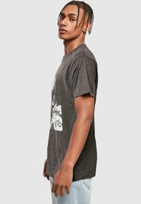 Grå grafisk t-shirt med et vintage-stil print på forsiden, korte ærmer og en afslappet pasform. Materiale i bomuldsblanding, blød tekstur.