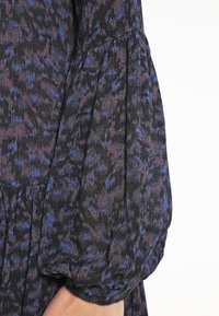 Vestito nero con motivo astratto blu e viola; presenta maniche lunghe a palloncino e un tessuto testurizzato con una leggera lucentezza.