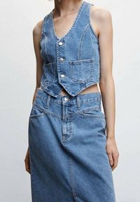 Denim cropped vest with v-neck, silver buttons, and front pockets paired with a high-waisted denim skirt in light blue wash.