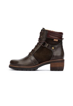 Bottine en cuir marron et en daim avec un talon empilé, un bout arrondi et un design à lacets. Présente des accents de couture et des œillets en métal.