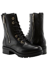 Schwarze Leder-Ankle Boots mit flacher Sohle, vorderem Schnürverschluss und seitlichen Reißverschlüssen. Mit goldenen Ösen und einem kleinen Markenlogo an der Ferse.