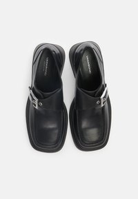 Pantofi din piele neagră, slip-on, cu o curea lată și detalii din metal argintiu. Vârful rotund și brant căptușit. Talpa exterioară din cauciuc plat.