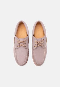 Lyse lilla lædermoccasinsko med tanfarvede snørebånd og syninger, set oppefra på en hvid baggrund.