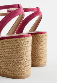 Fuksia pikendatud sandaalid suede materjalist, millel on punutud jute kontsad. Omab ristlati disaini ja siledat, ümarat tallat. Toonitud beež aluspind.