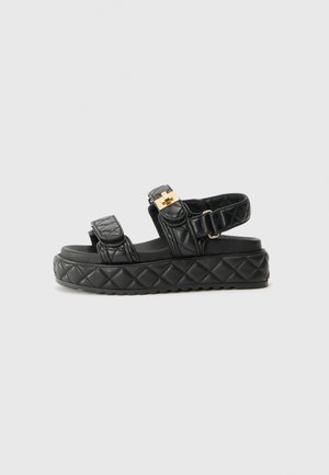 Zwarte, gewatteerde platform sandalen met twee verstelbare banden, gouden hardware accenten en een gestructureerde rubberen zool.