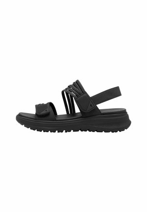 Sandales noires avec un design de strap texturé, bandeau de cheville réglable, semelle plate et semelle en caoutchouc pour une meilleure adhérence. Matériau léger et respirant.