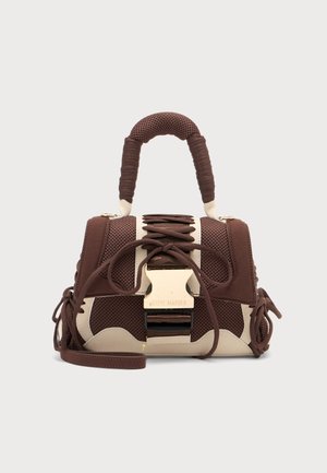 Sac à main texturé marron et beige avec anse enveloppante, devant lacé et grande boucle dorée sur fond uni.