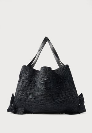 Grand sac fourre-tout noir tissé avec des poignées larges et plates et un dessus ouvert, présenté sur un fond clair uni.