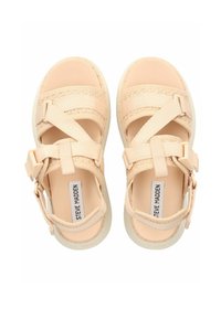 Pfirsichfarbene Sandalen mit elastischen Riemen, strukturiertem Obermaterial, Gummisohle und verstellbarem Schnallenverschluss. Das Etikett trägt die Aufschrift "Steve Madden."