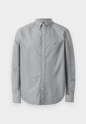 Button-up shirt in black and white vertical stripes, cotton material, long sleeves, classic collar, featuring a small logo on the chest.