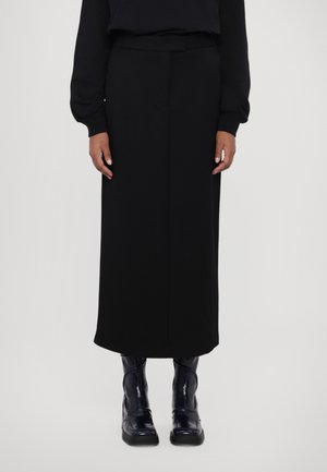 Svart maxi-skjørt med en rett silhuett, laget av et glatt stoff. Brukt med skinnende marineblå ankelstøvler. Enkelt, minimalistisk design.
