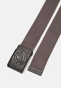 Cinturón de tela tejido gris con hebilla de metal negro que presenta un logo circular embossado y "ELEMENT" grabado en el extremo de tela.