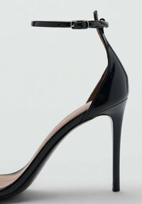 Sandală cu toc înalt din piele lacuită neagră, cu o curea subțire la gleznă, vârf ascuțit și toc stiletto elegant. Textură netedă și design minimalist.