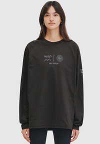 Black long-sleeve sweatshirt with a crew neck, featuring white printed logos and text. Made of soft fabric with a relaxed fit.