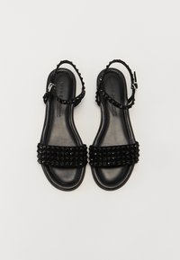 Svarte sandaler med doble brede stropper som har rhinestones, en teksturert såle og justerbare ankelstropper, alt på en glatt svart base.