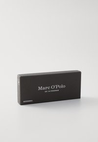 Caja rectangular negra con texto blanco "Marc O'Polo EST. EN ESTOCOLMO" y "ACCESORIOS". Textura suave, diseño minimalista, sin patrones.