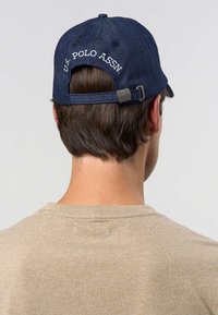 Marineblaue Jeanskappe mit gesticktem "U.S. POLO ASSN." Schriftzug auf der Rückseite, ausgestattet mit einem verstellbaren Riemen und Metallbeschlägen.