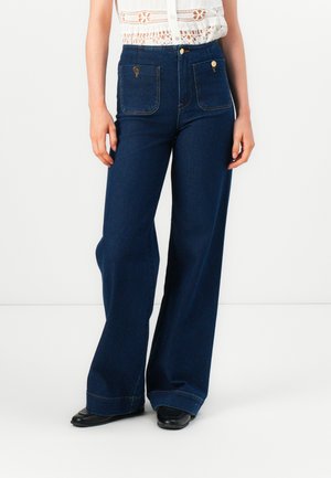 Donkerblauwe high-waisted denim broeken met wijde pijpen, voorzien van twee voorzakken, gouden hardware en contrasterende stiksels.