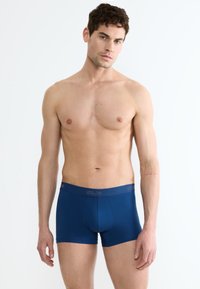 Boxer briefs in cotone blu navy con un design aderente e una cintura elastica che presenta un branding discreto. Tessuto liscia e lunghezza a metà coscia.