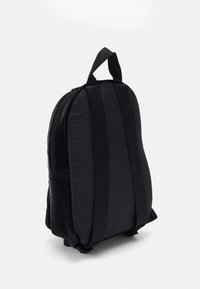 Zaino imbottito nero con una texture liscia, spallacci regolabili e una maniglia superiore, caratterizzato da un design minimalista e senza hardware visibile.