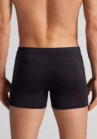 Zwarte katoenmix boxershorts met een snug fit, met een gladde textuur en elastische tailleband. Gezien vanuit de rug.