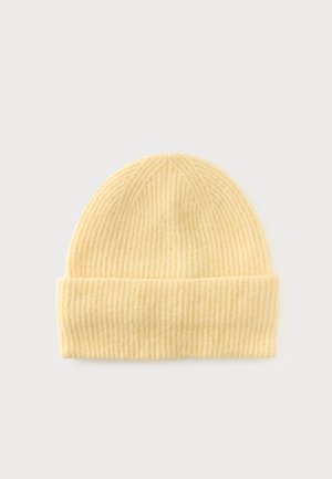Bonnet en tricot côtelé jaune doux avec revers plié, présenté sur un fond clair uni.