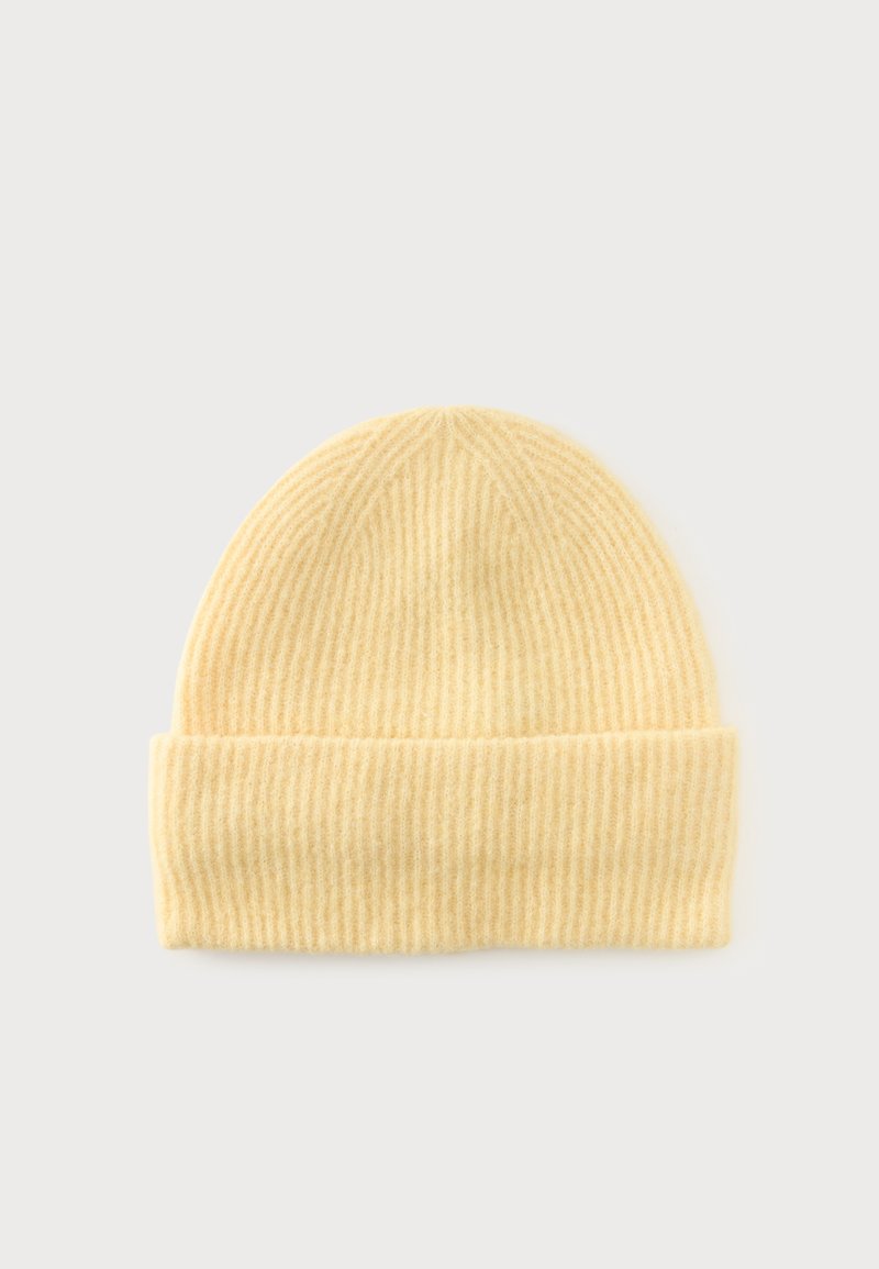 Bonnet en tricot côtelé jaune doux avec revers plié, présenté sur un fond clair uni.