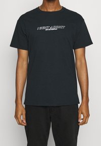 Černé bavlněné tričko s kulatým výstřihem a krátkými rukávy. Přední design obsahuje bílé text: "NIGHT ADDICT DYSTOPIA." Jednoduchá záda.