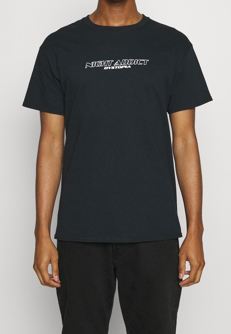 Černé bavlněné tričko s kulatým výstřihem a krátkými rukávy. Přední design obsahuje bílé text: "NIGHT ADDICT DYSTOPIA." Jednoduchá záda.