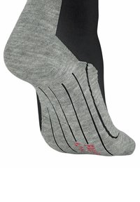 Chaussettes de sport grises et noires avec une texture côtelée, incluant des rayures noires sur la semelle et un détail de logo rouge près de l'orteil.