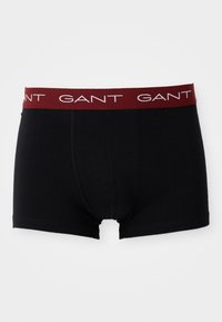 Boxers ajustados de color negro, hechos de algodón, que presentan una amplia cinturilla elástica en color burdeos con "GANT" impreso en blanco. Textura suave y diseño entallado.