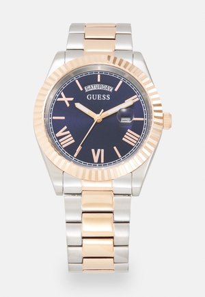 Silver and rose gold metal watch featuring a navy blue dial, Roman numerals, date window, and a textured bezel design.