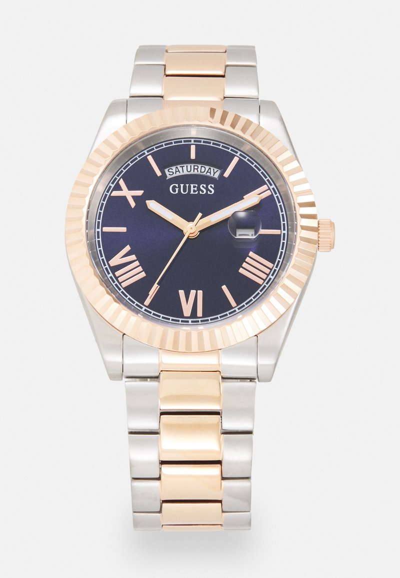 Relógio em metal prateado e rosa com mostrador azul-marinho, números romanos, janela de data e design de bezel texturizado.