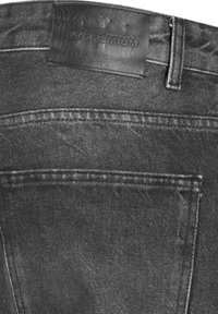 Vaqueros de mezclilla negra con una textura suave, que cuentan con una etiqueta de cuero en la cinturilla y un bolsillo trasero con detalles de costura.
