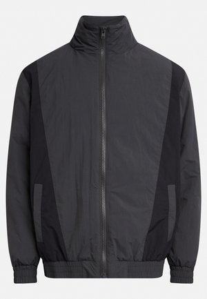 Black windbreaker jacket featuring a high collar, zip front, side pockets, and elastic cuffs. Made of lightweight, smooth fabric with color-blocked accents.