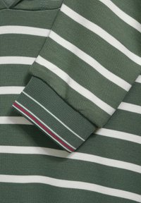Tessuto a maglia a strisce orizzontali verdi e bianche con un polsino a manica piegato caratterizzato da strisce accentuate rosse e bianche.