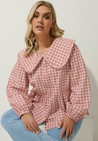 Ljusrosa gingham-blus med en stor volangkrage, knappstängning framtill och puffärmar; figursydd midja och samlad peplumdetalj.